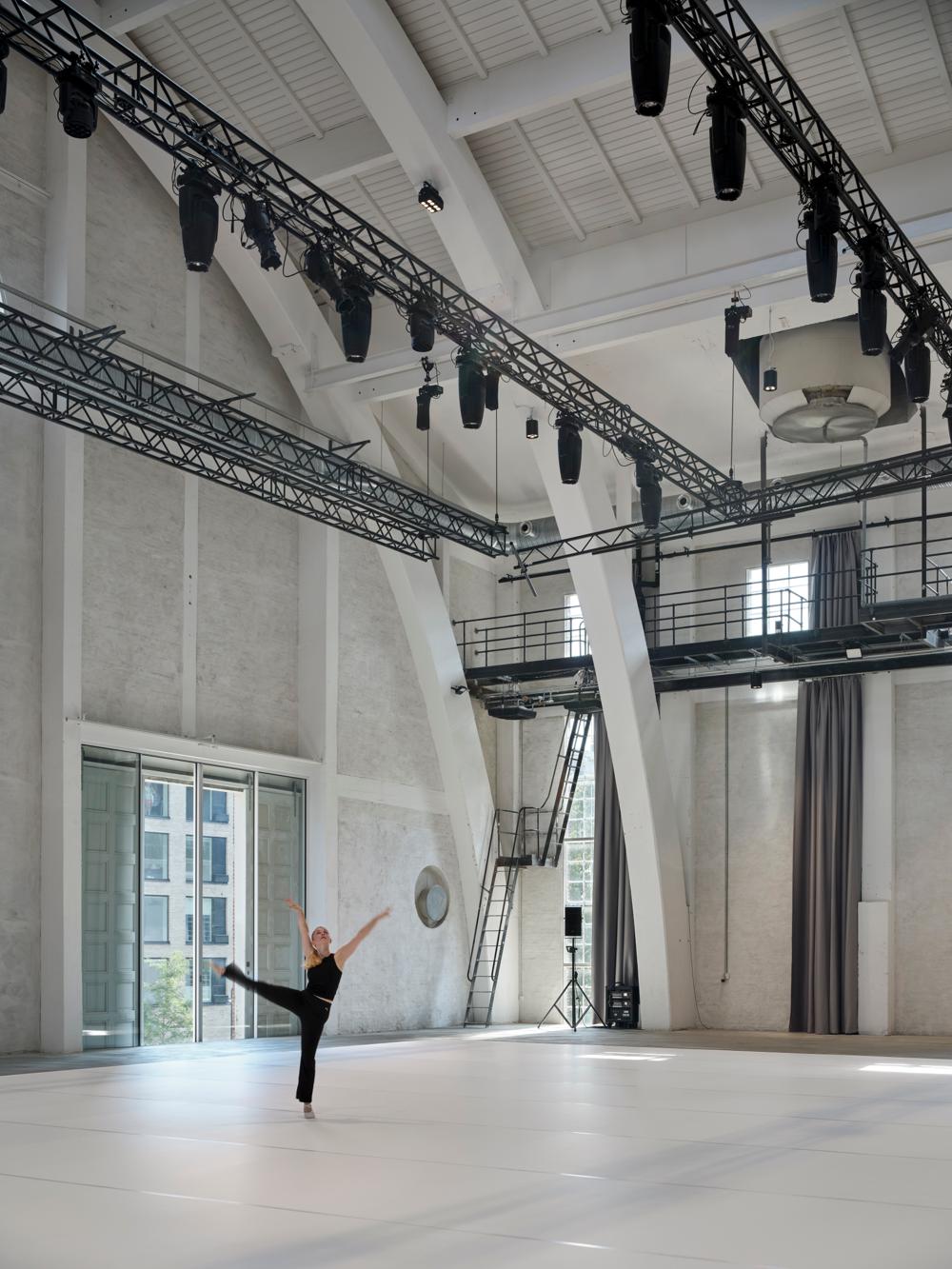 De gulvlange, draperede gardiner i Kedelhuset er inspireret af klassiske scenetæpper og spiller både en æstetisk og funktionel rolle. De kan mørklægge de høje facadevinduer og indgår samtidig som en del af den samlede akustiske regulering i bygningen – alt sammen nøje afstemt for at skabe optimale forhold til dans og performance. De gulvlange, draperede gardiner i Kedelhuset er inspireret af klassiske scenetæpper og spiller både en æstetisk og funktionel rolle. De kan mørklægge de høje facadevinduer og indgår samtidig som en del af den samlede akustiske regulering i bygningen – alt sammen nøje afstemt for at skabe optimale forhold til dans og performance.