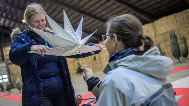 Sognepræst Rikke Visby Wickberg får instruktion i samle et stort julehjerte korrekt. Foto: Martin Damgård