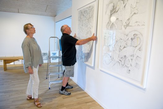 Ingelise Roikjer og Kaj Hyldig i gang med ophængningen af en af Karin Birgitte Lunds illustrationer til ”Islændingesagaerne”. <i>Bo Lehm</i>