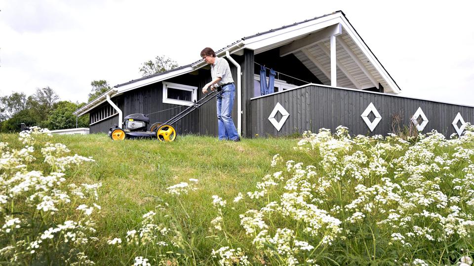 Inger Christensen har sammen med sin mand, Ole Andersen, sommerhus på Nordre Strandvej i Sæby. Her er Inger ved at slå græsset omkring huset. Ægteparret nægter derimod at slå det kommunale græs i græsrabatten (forrest). Foto: Bent Bach <i>Bent Bach</i>