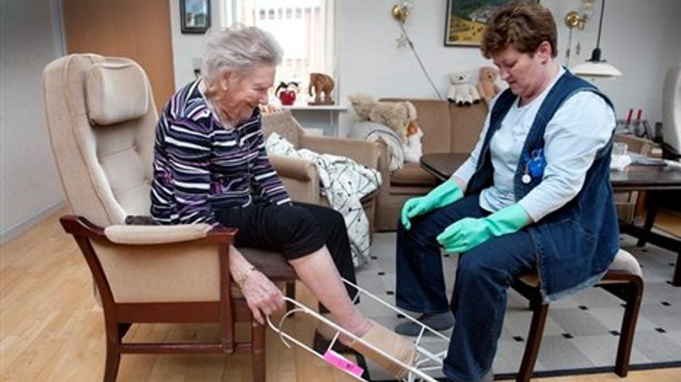 Hjemmetræner Mona Gadekjær fra Hjørring Kommune har lært 91-årige Ida Bundgaard selv at tage støttestrømper på. Foto: Bente Poder