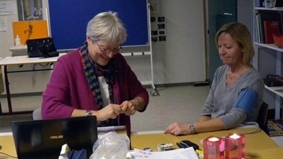 Sygeplejerske Charlotte Voetmann og Hanne Klemann Lykke, rengøringsassistent på Hedeboskolen taler om sundhed efter måling af blandt andet blodtryk. Privatfoto