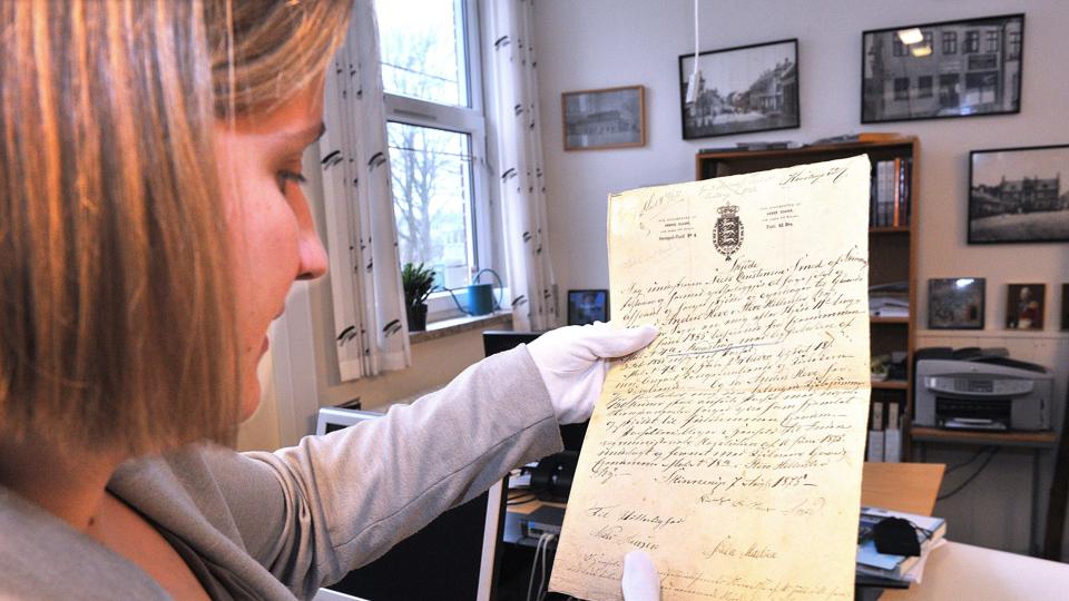Museumsinspektør Marianne Sørensen med et skøde fra 1875, hvor Niels Christensen Smed af Skinnerup solgte sin gård til Anders Hove af St. Hillerslev, nærmere bestemt matrikelnr. 18a af Kåstrup by.? Foto: Ole Iversen