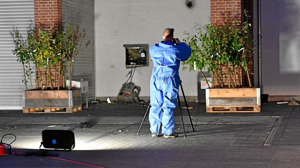 Politiet ved gerningsstedet, hvor pengeautomaten blev sprængt ud af muren. Overvågningskameraet øverst th. blev også ødelagt af tyvene. Foto: Jan Pedersen