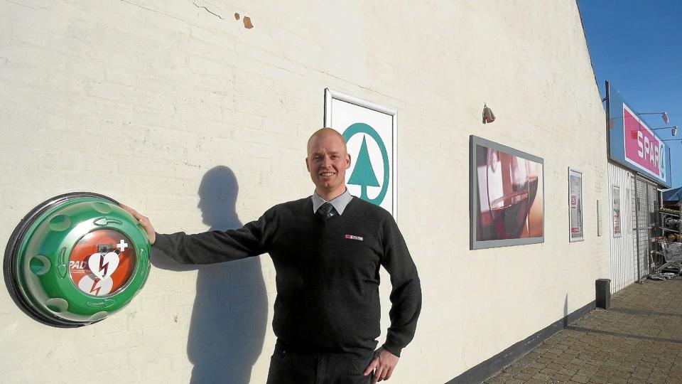 Christian Bast med den nye hjertestarter på gavlen af butikken. Foto: Kirsten Olsen <i>Kirsten Olsen</i>