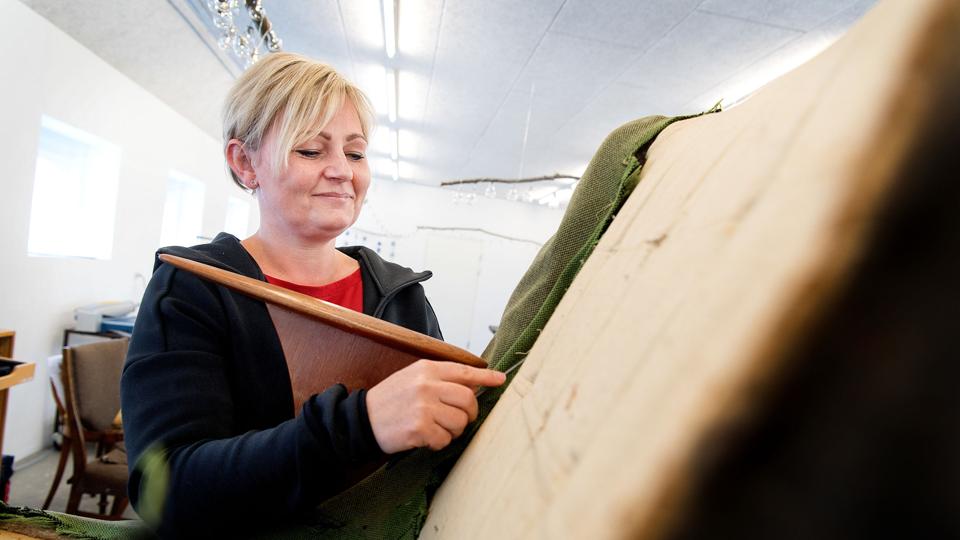 Tina Hougaard i gang med at ombetrække en gammel møbelklassiker på værkstedet.