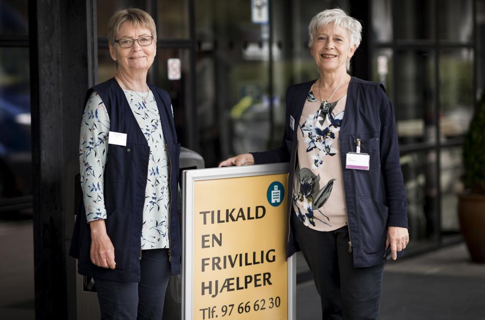 Henny Schjødt Nielsen og Tove Rahmberg er frivillige på Aalborg Universitetshospital og klar til at tage imod patienter, mens føreren leder efter en p-plads. Foto: Lasse Høj Nielsen