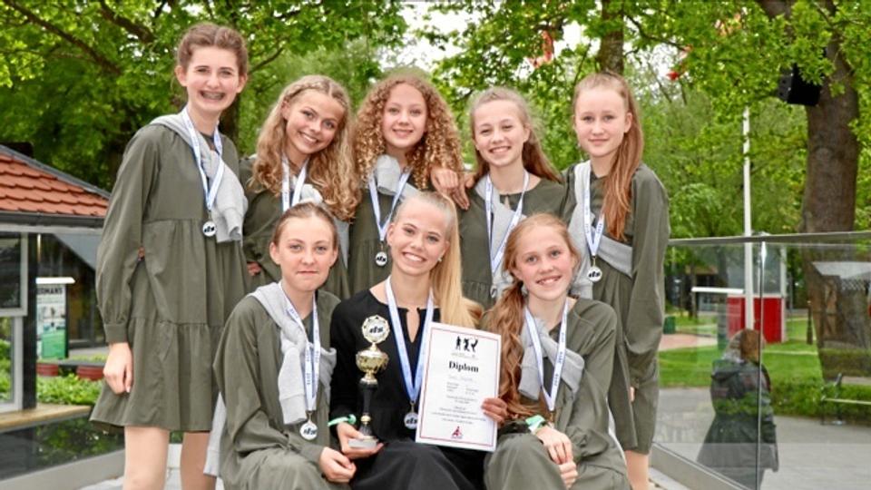 På foto af Team Passion fra konkurrencen i Tivoli Friheden i Aarhus ses stående fra venstre Nicoline Dalby Madsen, Ingeborg Secher, Lærke Sauer, Freja Filtenborg Pedersen, Yasmin Guldager. Siddende Tilde Holm Jensen, træner Rebekka Bjerre med vinderdiplomet og Dicte Sand. Privatfoto