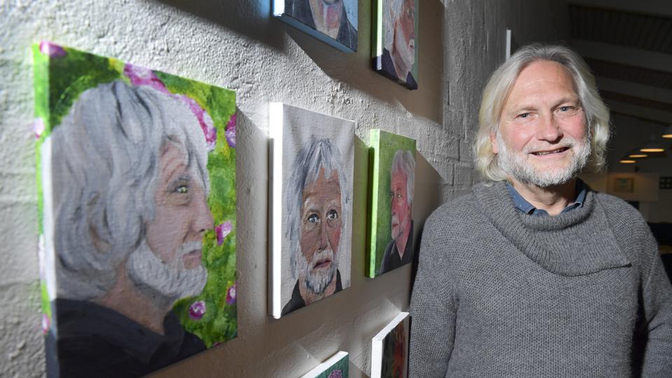 Berno Jacobsen har de seneste 15 år været leder på efterskolen i Bælum, hvor han her er fotograferet ved siden af nogle portrætter af ham malet af elever på kunstlinjen.