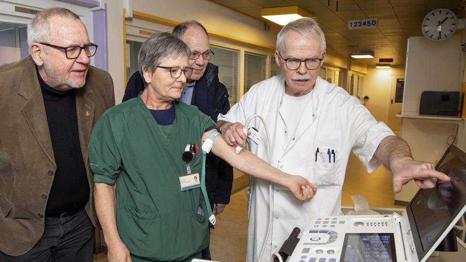 Afsnitsledende sygeplejerske Birgitte Kløve-Mogensen lægger arm til scanneren, som overlæge John Mikkelsen betjener. Tom Soelberg og Svend Ovesen følger med i, hvad der sker på skærmen.