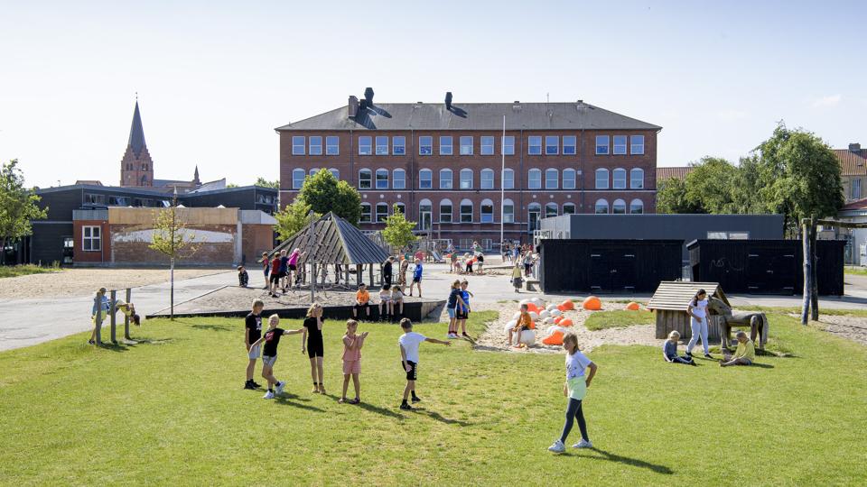 I løbet af 2021 skal der opføres en ny bygning med fem klasseværelser, der hvor Limfjordsteatret lå, til venstre i billedet. Der er nu bare en grusplads tilbage. Derefter vil de grå pavilloner blive fjernet. Derved sparer kommunen en årlig leje på 735.000 kroner. Foto: Peter Mørk