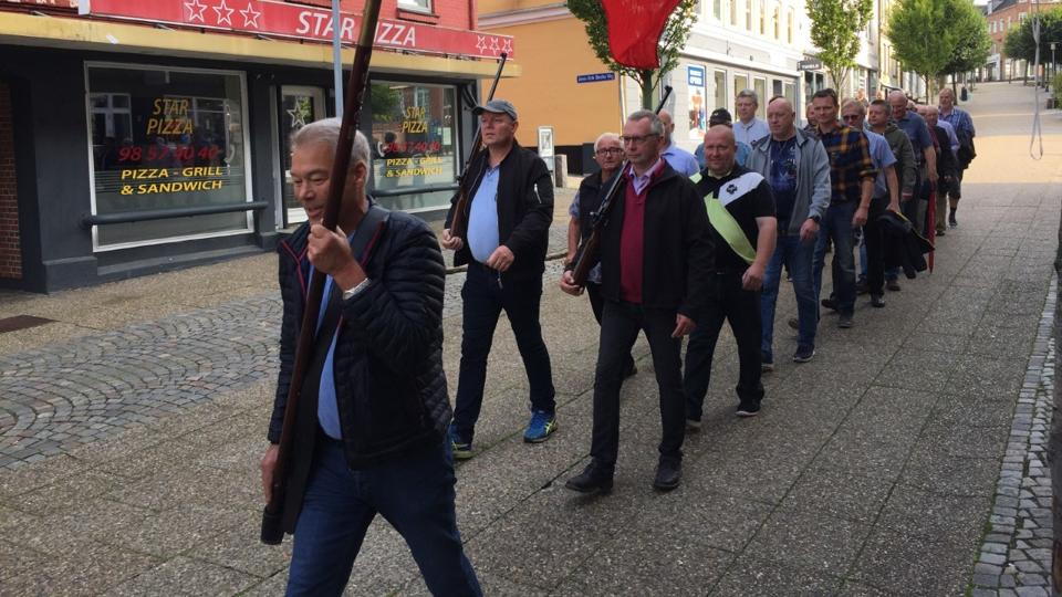 Den første weekend i august afholder skyttelauget i Hadsund fugleskydning på sin bane ved Skovpavillonen. Dagen starter med en fælles march fra torvet i Hadsund til Hobrovej. Næstformand Viggo Hedegaard bærer fanen. Jan Poulsen og Erik Andersen går med geværerne. Privatfoto