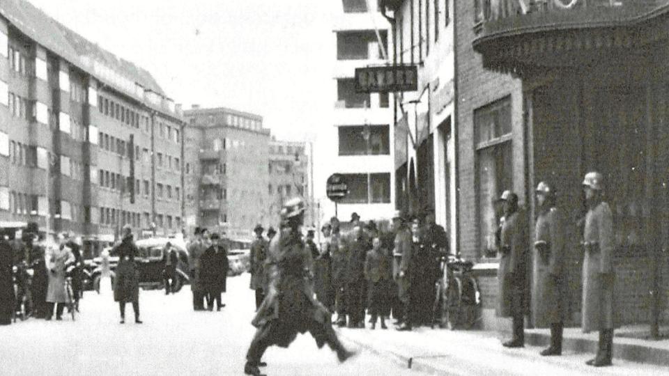 Tyske tropper på Vesterbro, Aalborg, april 1940. Besættelsen kom overrumplende, men fotohandler Clausen indledte meget hurtigt en hemmelig historisk dokumentationsindsats. Når tyske soldater indleverede film til fremkaldelse, lavede han et ekstra sæt billeder til sig selv. Inge Bente Clausen har givet bogens forfatter mulighed for at bruge omkring 200 af disse fotos, som nu er overdraget til Frihedsmuseet.