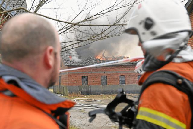 Brandfolk fra Nordjyllands Beredskab skal have hjælp fra en kran til at fjerne ting fra togkonstruktionen, før de kan bevæge sig ind i bygningerne i sikkerhed. Foto: Jan Pedersen