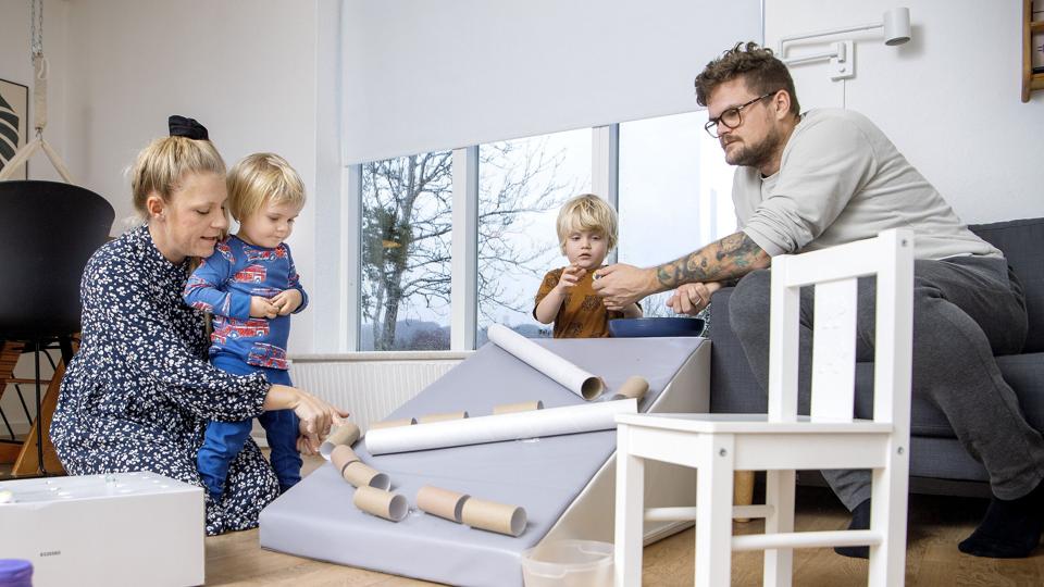 Diana Noe, hendes mand Anders og deres to børn Aksel (tv.) og Anton leger i stuen i hjemmet, en villa på Udsigten i Mariager. De har bygget en kuglebane af paprør fra wc- og plakatruller, og nu skal den fodres med glaskugler. På sin Instagramprofil Kram og Krea deler Diana Noe masser af gode, billige lege-ideer som denne. Foto: Lars Pauli <i>Foto: Lars Pauli</i>