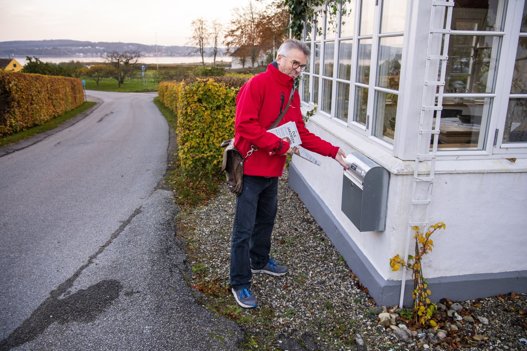 Skuespiller Ole Jakobsen vover et øje og putter en af sine valgbrochurer i postkassen, selv om der står "reklamer nej tak" på den. Der er 30 husstande i Stinesminde, og Ole Jakobsen kommer omkring hovedparten af dem. Foto: Henrik Bo <i>Foto: Henrik Bo</i>