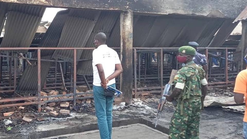 A journalist, policeman and a soldier observe the damage in front of the main prison after the fire, in Gitega <i>Sos Medias Burundi/Reuters</i>