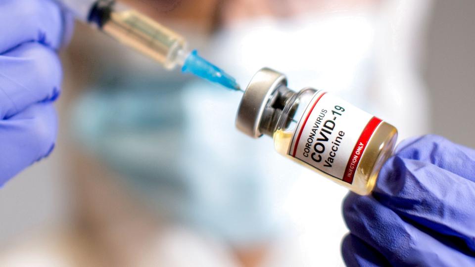 FILE PHOTO: A woman holds a medical syringe and a small bottle labelled <i>Dado Ruvic/Reuters</i>