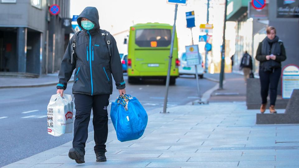 A man wearing a protective mask carries shopping bags as he walks on the streets of Oslo following an outbreak of the coronavirus disease (COVID-19) <i>Ntb Scanpix/Reuters</i>