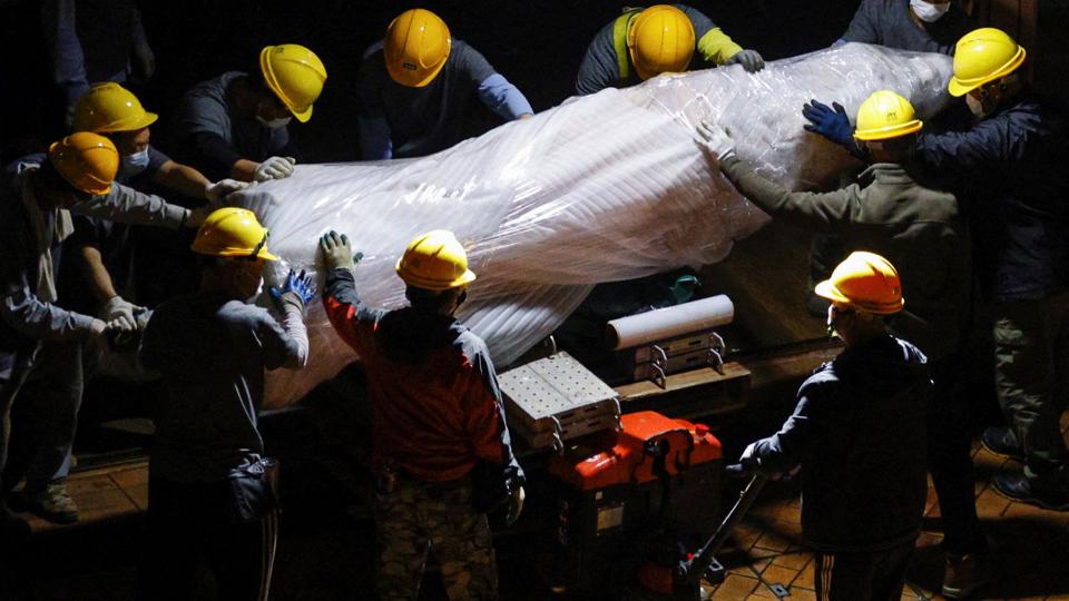 Workers remove a part of <i>Tyrone Siu/Reuters</i>