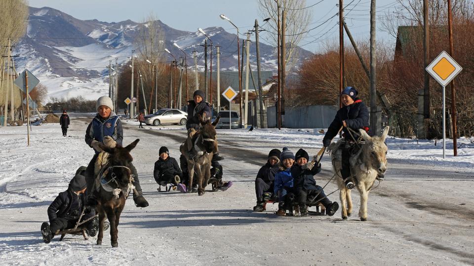 Children ride sleds pulled by donkeys in the village of Karasaz <i>Pavel Mikheyev/Reuters</i>