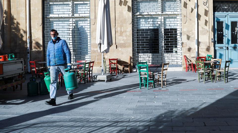A man wearing a protective face mask carries gas bottles amid the coronavirus disease (COVID-19) outbreak in Nicosia <i>Yiannis Kourtoglou/Reuters</i>