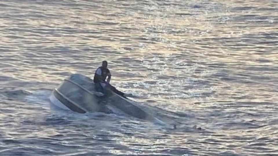 Man sits on a capsized boat off the coast of Florida <i>U.s. Coast Guard/Reuters</i>