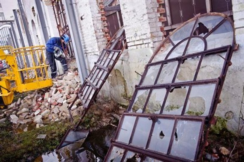 De karakteristiske buede vinduesrammer bliver lempet ud af hullerne i den faldefærdige ruin. De er solgt til en privatmand, der vil bruge dem som udsmykning i en ladebygning. Foto: Martin Damgård