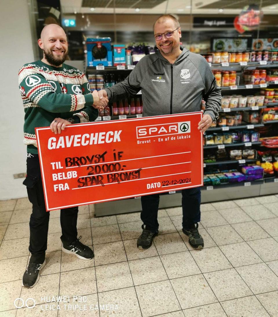 Den lokale Spar-købmand, Peter Guldhammer (venstre), uddeler håndtryk og gavecheck til Klubformand i Brovst IF, Hardy Larsen (højre).