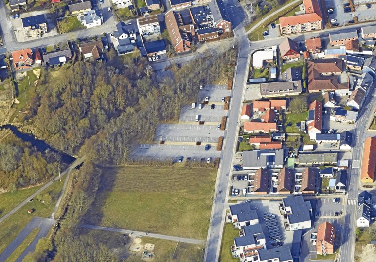 Den nye parkeringsplads med båse til 53 biler anlægges på en del af det grønne areal i forlængelse af de eksisterende parkeringspladser i Korsgade. Området blev tidligere brugt som cirkusplads. Skråfoto: Styrelsen for Dataforsyning og Effektivisering
