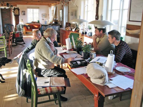 Thorup Kystfiskerlaugs nye direktør, Tommy Olsen (ved pcen), den afgående direktør Ole Eriksen (med telefonen). De andre to er fiskerne Henrik Nielsen (leger med hunden) og Michael Kristensen (rødstribet trøje). Privatfoto (2006)