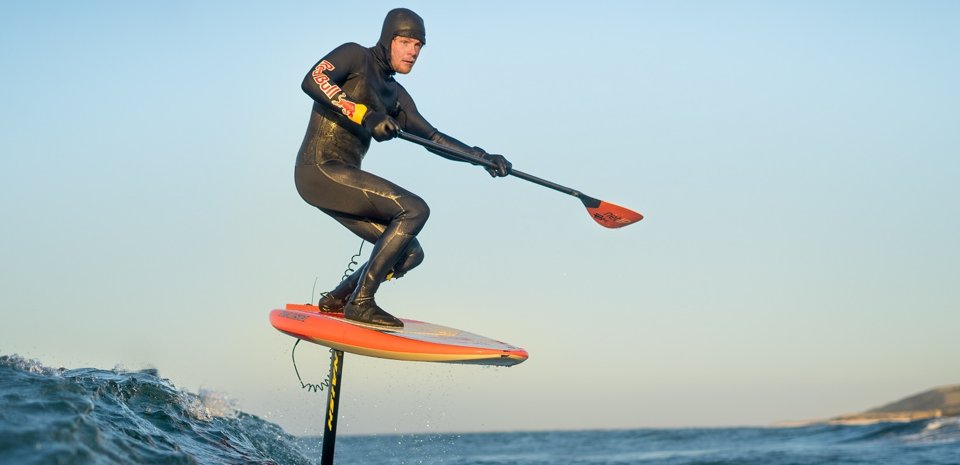 Turen skal foregå på et såkaldt hydrofoilbræt. Det har en t-formet finne under brættet, som udnytter bølgernes energi til at skabe fremdrift. Når han får gang i brættet, ser det ud som han står på et flyvende tæppe hen over bølgerne. Foto: Cat Yde, Waterhouse