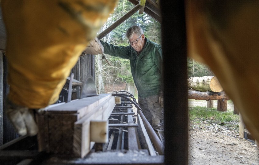 Finn Jacobsen fra Støvring har været frivilligt medlem af savværkslaguet siden starten i 2007. Her er han sammen med en anden frivillig i gang med at save brædder på langtømmersaven placeret under et halvtag på træladens langside.
