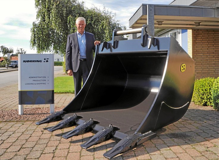 Administrerende direktør Klaus Kalstrup foran maskinfabrikken med en graveskovl fra Sjørrings eget brand. Privatfoto.