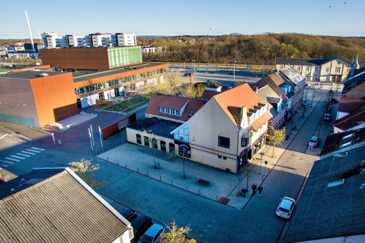 Jernbanegade 19 - der tidligere husede Messing Jens - skal rives ned - og det samme gælder resten af bygningerne i karréen bagved. Det skal give plads til parkeringspladser og den nye Hjørring Musiske Skole, der skal opføres foran Hjørring Banegård, der ses i baggrunden. Til venstre ses det relativt nyopførte Vendsyssel Teater.