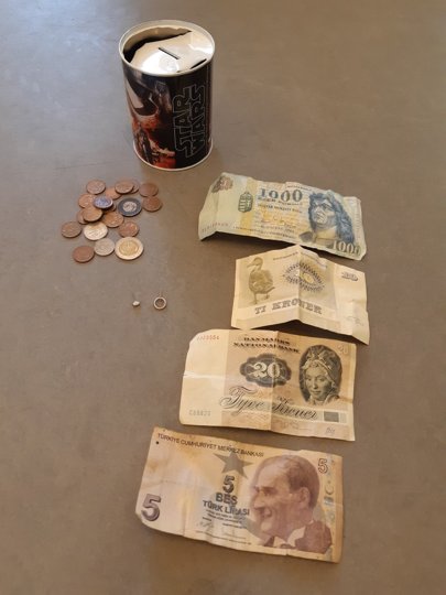En  sparebøsse med forskellige mønter og sedler mangler ejer. Foto: Politiet