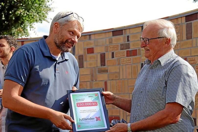Jutlander Fondens formand Poul Søndberg (til højre) overrækker her ved en tidligere lejlighed Mariagerfjord Gymnasiums rektor Søren Urup en donation på 150.000 kroner til etableringenaf kunstmuren, som ses bag dem. Foto: Erik Røgild