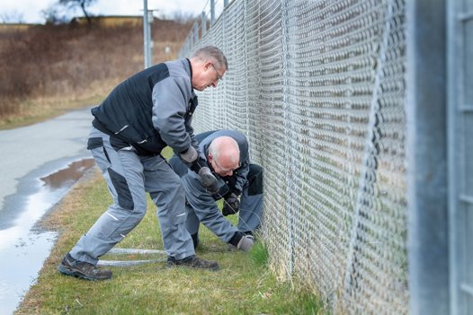 Medarbejdere fra Hjørring Vandselskab lapper hul i hegnet rundt om pumpestationen