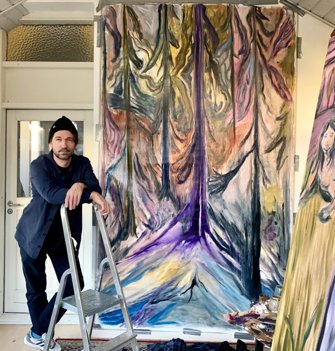 Kunstner Lasse Thorst foran ét af de to 25x15 meter lærreder med skov, der skal være med til at omdanne standen til en middelalderscene. Privatfoto
