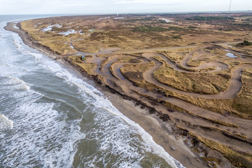 Dette foto blev taget i 2018. Motocrossbanen ses til højre, og de to yderste spor ud mod havet, hvor crossmaskinerne kører, er væk i dag. Foto: Peter Broen