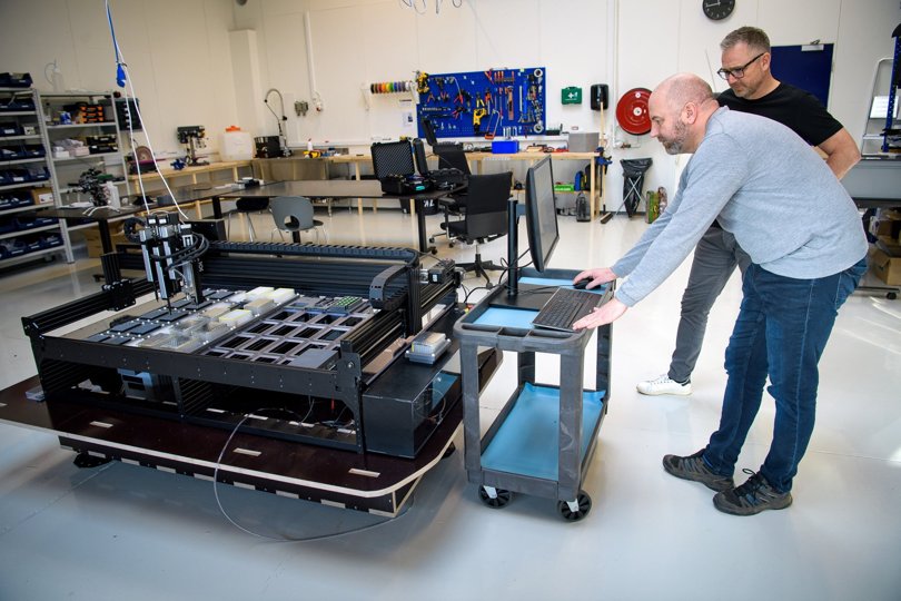 Søren Bastholm og Thomas Hansen ved den nye robot, som kan måle DNA-rester fra både dyr og planter i åer og fjorde - fuldstændig automatisk, hvilket giver et langt bedre billede af vandmiljøet end hidtil. Foto: Bo Lehm