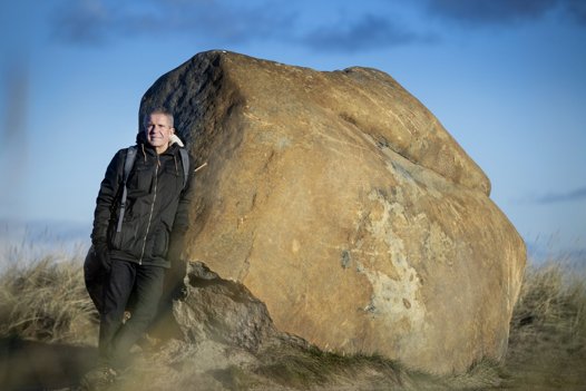 Stenen her er ganske dekorativ og blev flyttet her ned til stranden foran Kystvejen, da der var klokarbejde oppe i byen. Den historie deler han også, når han guider i "Nationalpark Hirtshals, som han kalder området, der ligger lige uden for hans vindue.