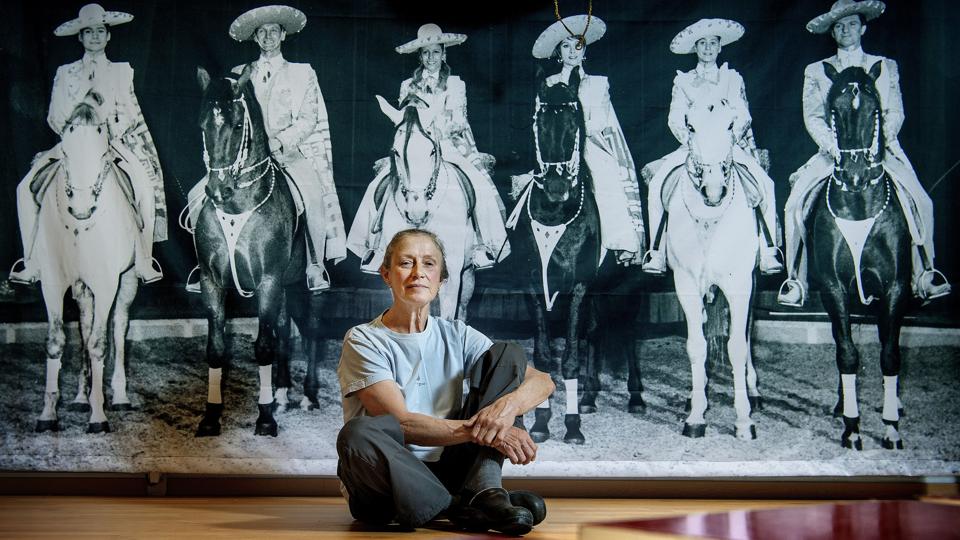 Katja Schumann, som i dag er 70, er ud af cirkusslægt. På fotostaten i baggrunden ses hun i mexikansk udklædning som nummer tre fra venstre. Hun var 12 år dengang. - Jeg er altid den, der smiler! siger hun. Foto: Lars Pauli <i>Foto: Lars Pauli</i>