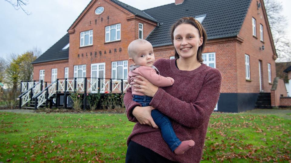 Pia Hansen med datteren Esther på armen foran sin og kæresten Rasmus' drømmebolig på Vesterled i Handest, syd for Hobro. Hele stueetagen var nyrenoveret, da de købte ejendommen i 2015. Der er kælder, stue og førstesal, grundplan er 190 kvm. Prisen var absolut rimelig - godt to millioner kroner. Foto: Bente Poder