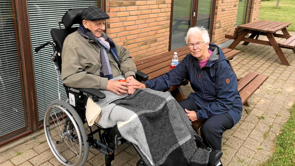 Hanne Stenbakken kan kun besøge sin mand Jørgen, når vejret er til ophold udendørs. Det er ikke tilladt pårørende at komme ind i boligen. Det bør man genoverveje, for ældre har ikke tid til at vente på godt vejr - og risikoen for at hun medbringer smitte er minimal, mener Hanne Stenbakken. Privatfoto
