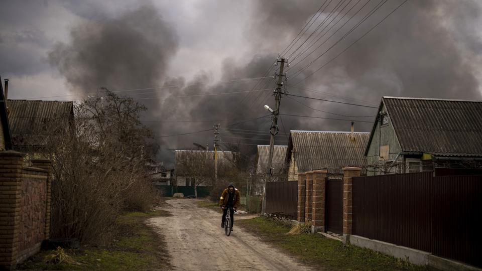 En ukrainsk mand cykler nær en brændende butik, efter at den er blevet bombet i Irpin, som ligger i udkanten af hovedstaden Kyiv. Rusland og Ukraine forsøger at lave en aftale for at evakuere civile fra blandt andet Kyiv. (Arkivfoto). <i>Emilio Morenatti/Ritzau Scanpix</i>