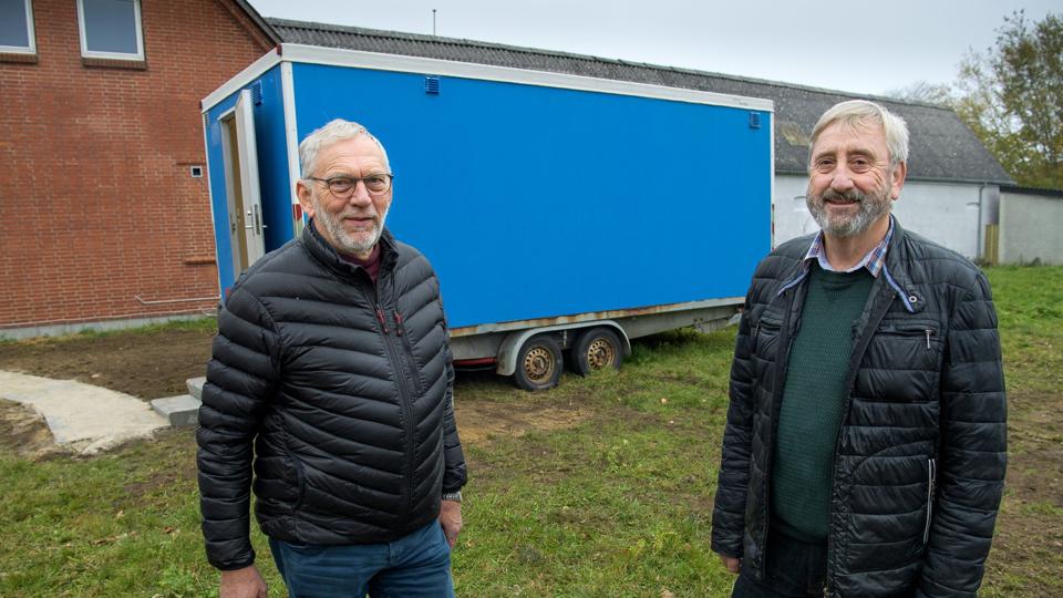 Morsøs socialudvalgsformand Henning Sørensen (V) og Perlens leder Svend Erik Jørgensen viser, hvor de tre boliger skal bygges som erstatning for skurvognen bag dem. <i>Arkivfoto: Bo Lehm</i>
