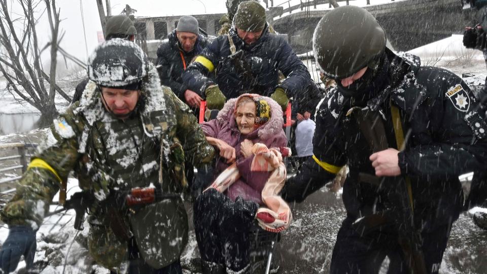 Ukrainske soldater hjælper en ældre kvinde med at krydse en ødelagt bro under evakueringen fra Irpin. <i>Sergei Supinsky/Ritzau Scanpix</i>