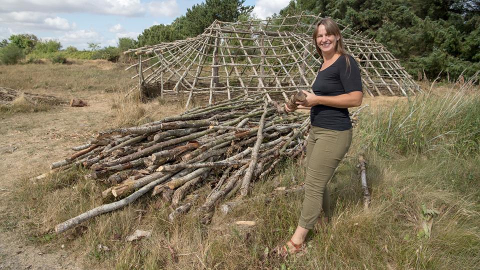 Louise Villadsen foran skelettet til det første stenalderhus i parken. Det er bygget med hjælp fra et tysk museum. Foto: Henrik Louis