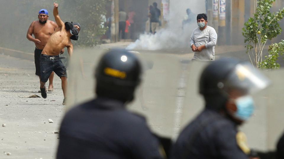 Demonstranter i sammenstød med kampklædt politi i Ate øst for Perus hovedstad, Lima, mandag. Her havde busser og lastvogne blokeret veje i protest mod stigende priser på brændstof. <i>Gian Masko/Ritzau Scanpix</i>